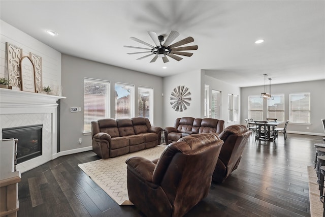 living area featuring a wealth of natural light, baseboards, dark wood finished floors, and a tiled fireplace