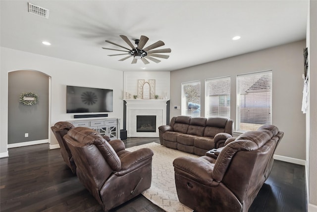 living area featuring visible vents, baseboards, arched walkways, and dark wood-style floors