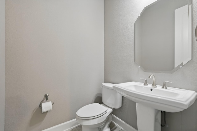 bathroom with toilet, baseboards, and a sink