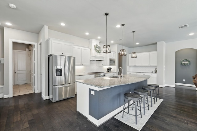 kitchen featuring visible vents, appliances with stainless steel finishes, arched walkways, custom exhaust hood, and a sink