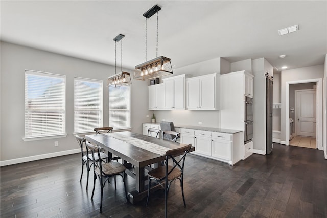 dining area featuring visible vents, baseboards, dark wood finished floors, and a barn door