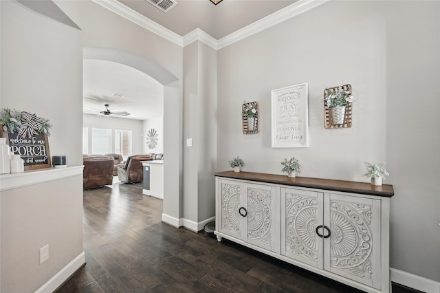 hall with visible vents, baseboards, arched walkways, dark wood-style flooring, and ornamental molding