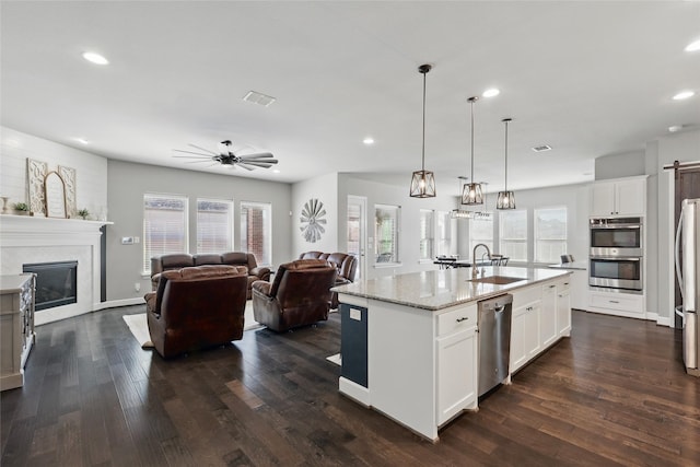 kitchen featuring a sink, dark wood-type flooring, a glass covered fireplace, and stainless steel appliances