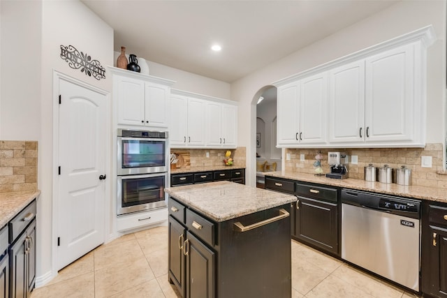 kitchen with appliances with stainless steel finishes, white cabinets, backsplash, and light tile patterned flooring