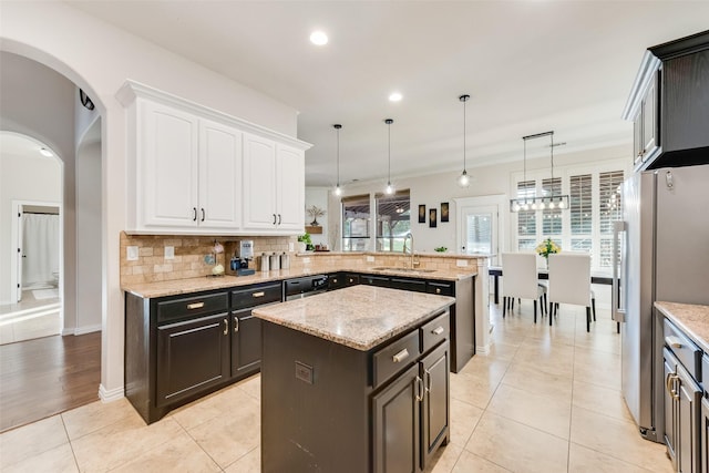 kitchen with tasteful backsplash, freestanding refrigerator, a peninsula, white cabinetry, and a sink