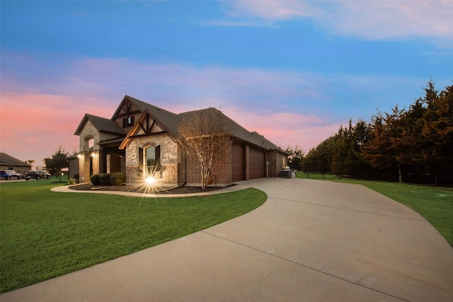 property exterior at dusk featuring a garage, stone siding, a yard, and concrete driveway