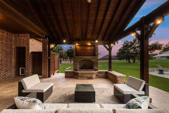 patio terrace at dusk featuring a yard and an outdoor living space with a fireplace