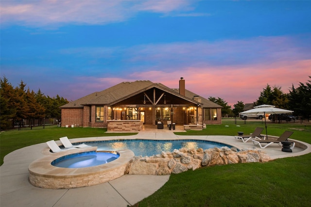 pool at dusk featuring an outdoor pool, a patio area, an in ground hot tub, and a yard