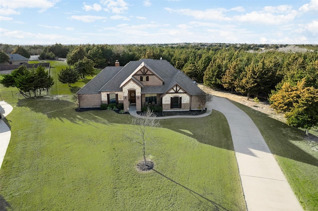 view of front of property with a front yard, stone siding, brick siding, and a chimney