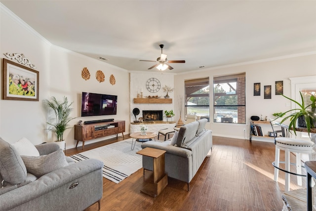 living area with ornamental molding, a large fireplace, visible vents, and dark wood-style flooring