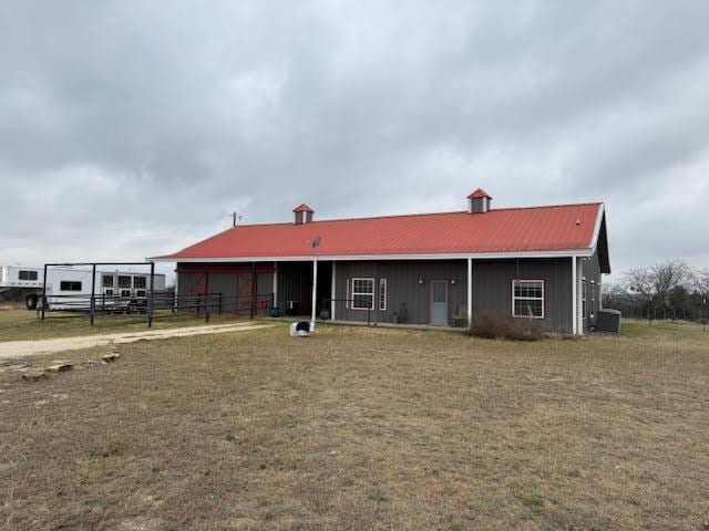 view of front of house with central AC, metal roof, and fence