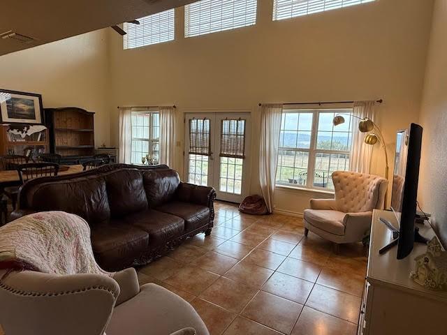 tiled living area featuring french doors and a high ceiling