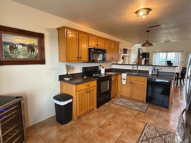 kitchen featuring visible vents, brown cabinets, black appliances, a sink, and light tile patterned flooring