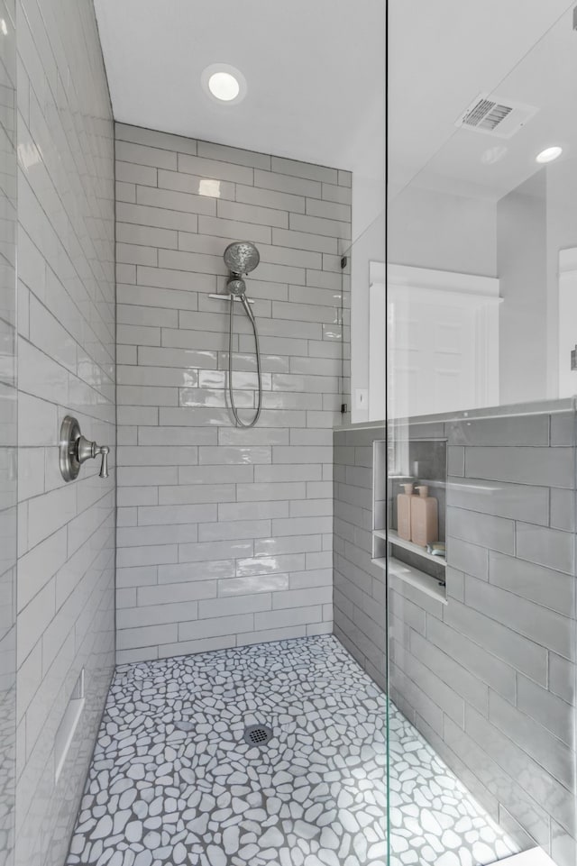 full bath featuring tiled shower and visible vents