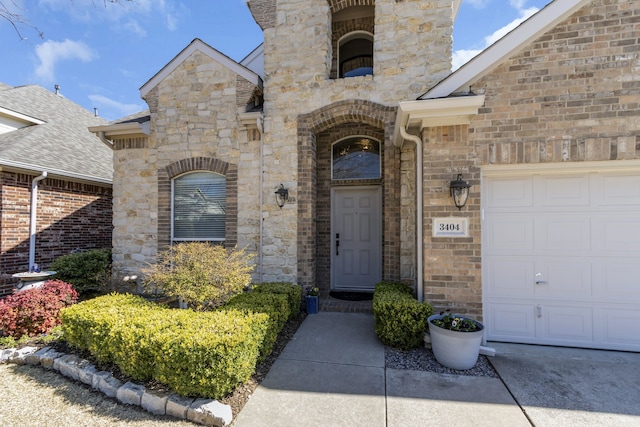 entrance to property with a garage, stone siding, and brick siding