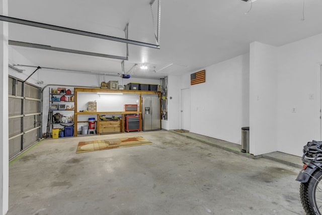 garage with stainless steel refrigerator with ice dispenser and a garage door opener