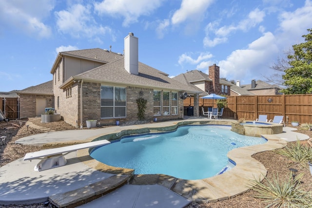 view of pool featuring a fenced backyard, a pool with connected hot tub, a diving board, and a patio