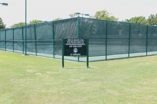 view of sport court with a lawn and fence