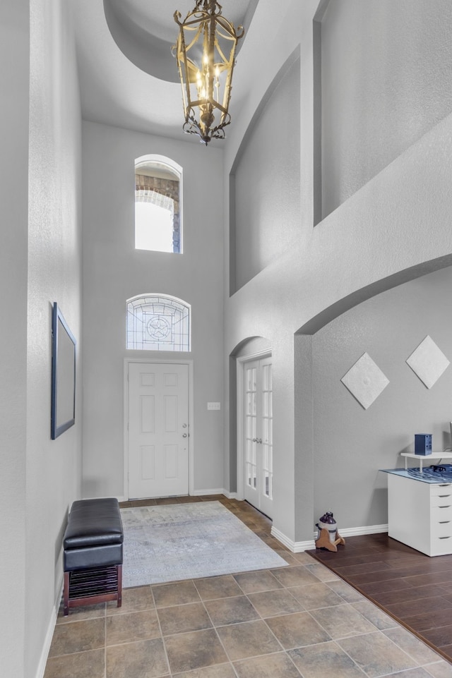 entrance foyer with a high ceiling, a notable chandelier, and baseboards