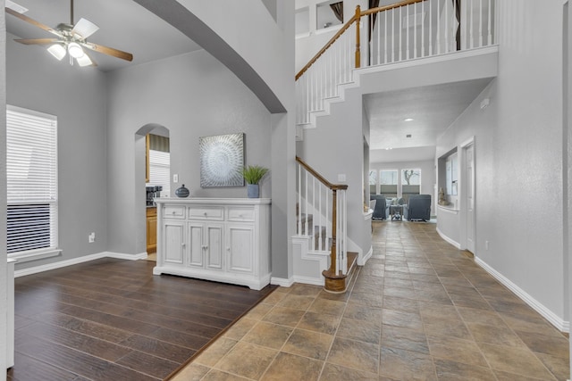 foyer entrance with arched walkways, stairs, dark wood finished floors, and baseboards