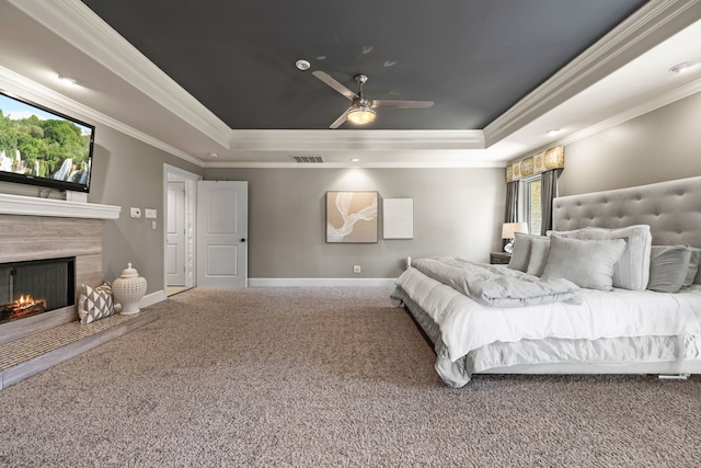 carpeted bedroom featuring a tray ceiling, visible vents, a fireplace, and baseboards