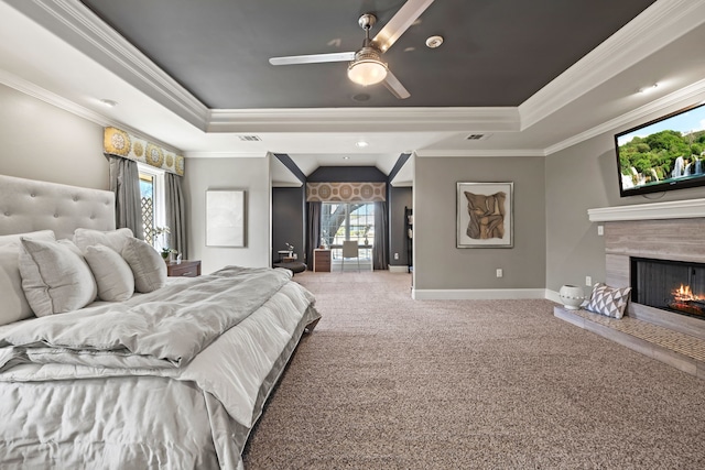 carpeted bedroom with a high end fireplace, a tray ceiling, ornamental molding, and baseboards