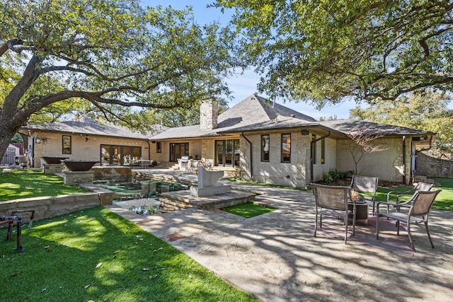 rear view of property featuring crawl space, a patio area, a yard, and a chimney