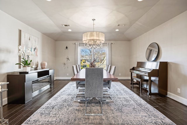 dining room with dark wood-style flooring, visible vents, and vaulted ceiling