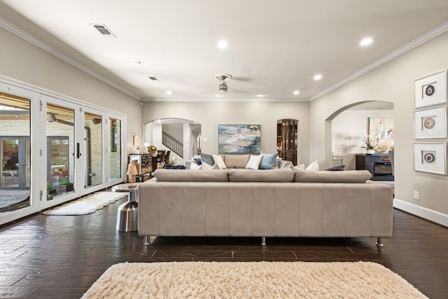 living room featuring arched walkways, dark wood-type flooring, and baseboards