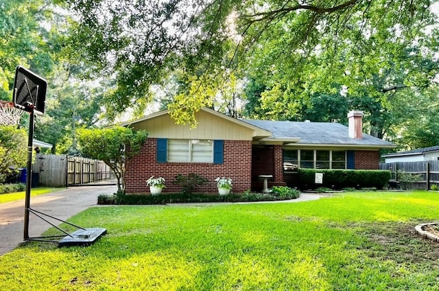 ranch-style house featuring brick siding, a front yard, and fence