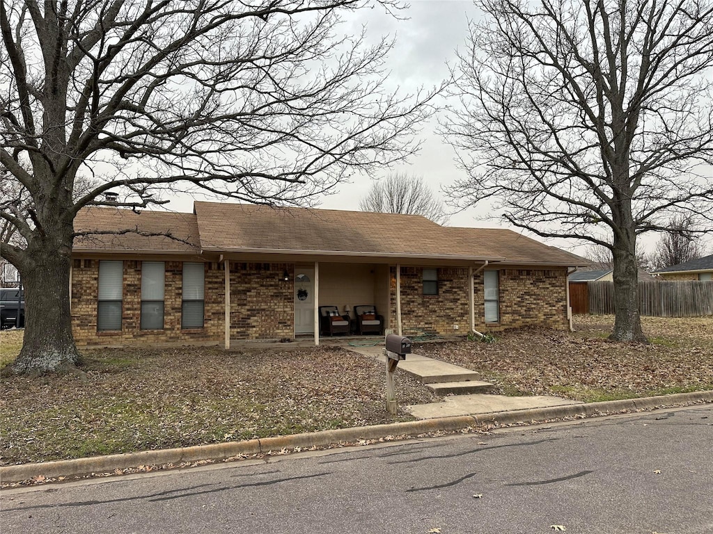 view of front facade with brick siding and fence