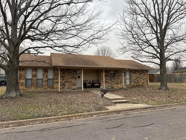 view of front facade with brick siding and fence