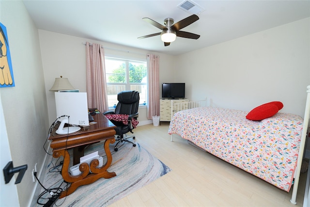 bedroom with ceiling fan, wood finished floors, visible vents, and baseboards