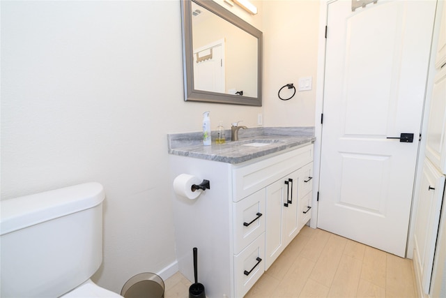 half bath with vanity, toilet, and wood finished floors