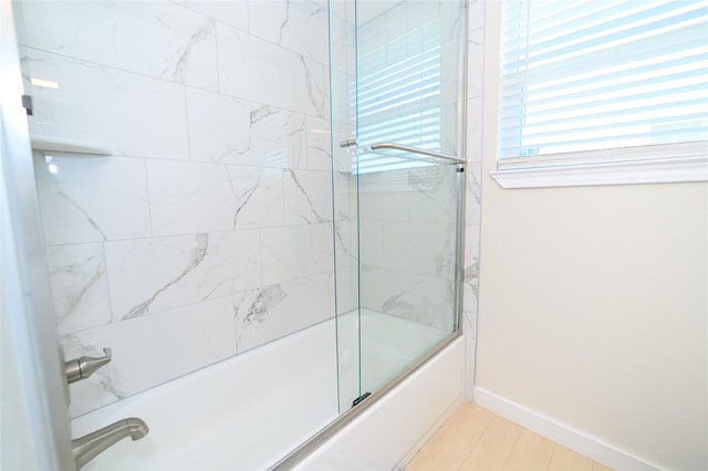 bathroom with enclosed tub / shower combo and baseboards