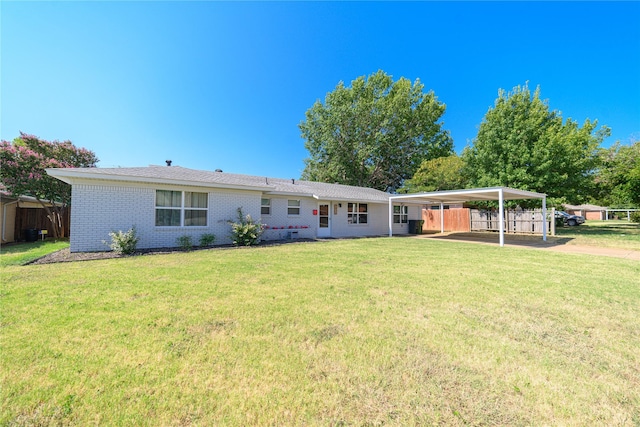 rear view of house with a carport, brick siding, fence, and a lawn