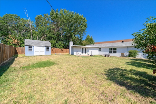 view of yard featuring a shed, an outdoor structure, a fenced backyard, and french doors