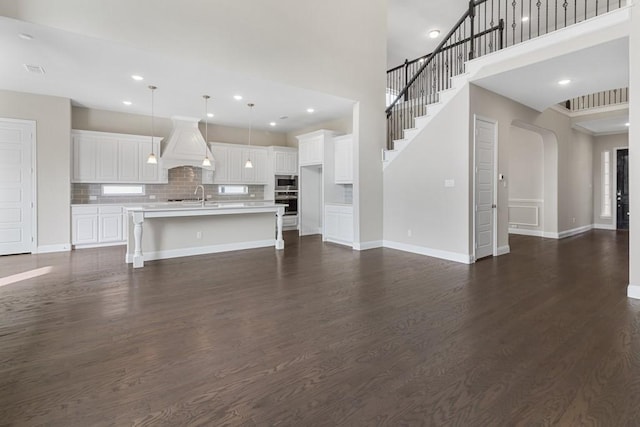 unfurnished living room with recessed lighting, a sink, dark wood finished floors, and baseboards