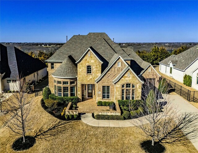 french country home featuring stone siding and fence