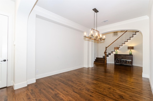 empty room with baseboards, wood finished floors, visible vents, and crown molding