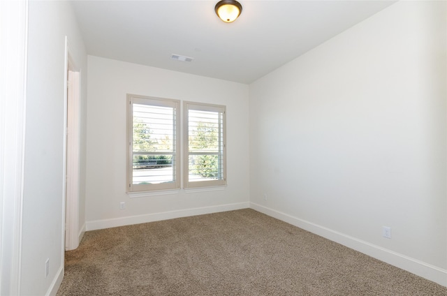 spare room featuring carpet flooring, visible vents, and baseboards