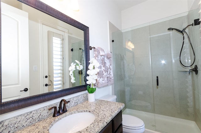 full bathroom featuring a shower stall, toilet, and vanity