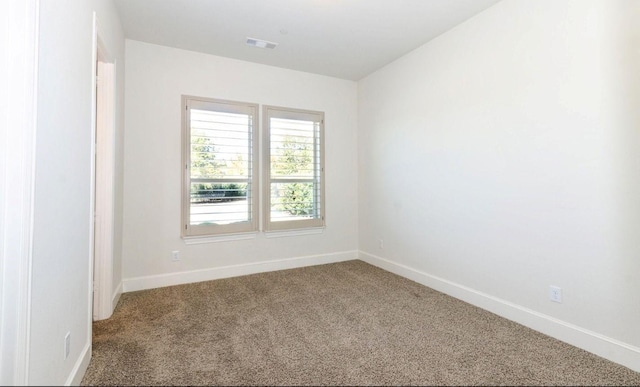 unfurnished room with carpet floors, visible vents, and baseboards