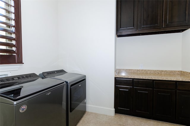 laundry area with cabinet space, light tile patterned floors, baseboards, and washer and clothes dryer