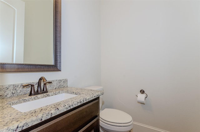 bathroom featuring baseboards, toilet, and vanity