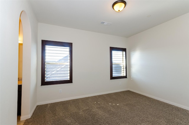 unfurnished room featuring carpet, visible vents, and baseboards