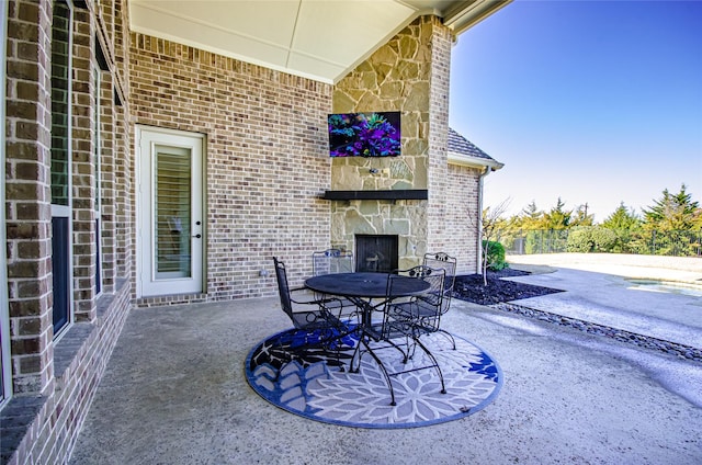 view of patio with an outdoor stone fireplace and outdoor dining space
