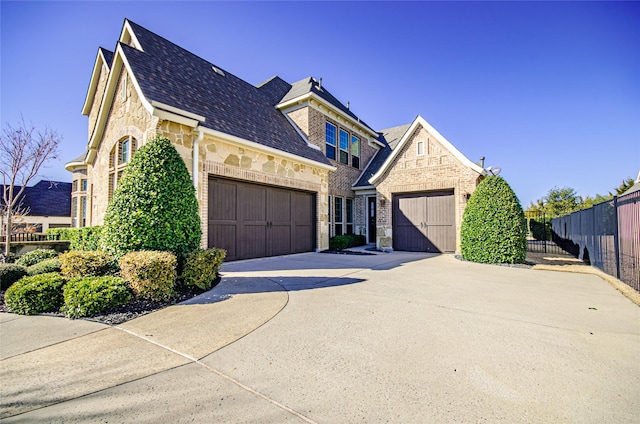 view of front facade with brick siding, concrete driveway, fence, a garage, and stone siding