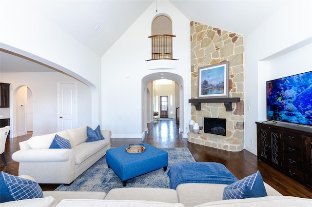 living area with high vaulted ceiling, a fireplace, arched walkways, and wood finished floors