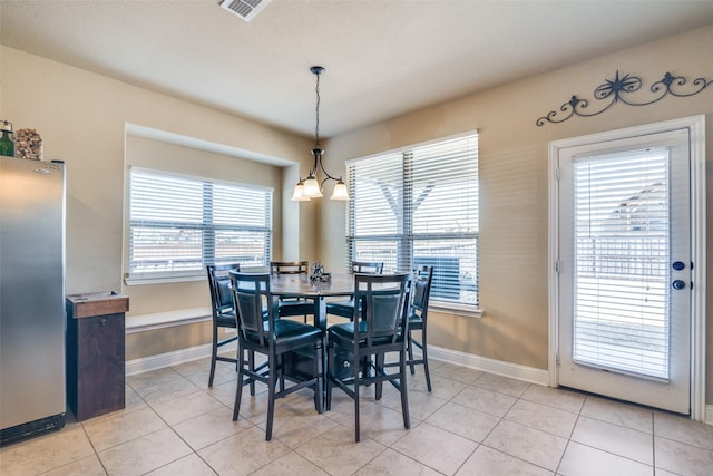 dining space with light tile patterned floors, baseboards, visible vents, and a notable chandelier